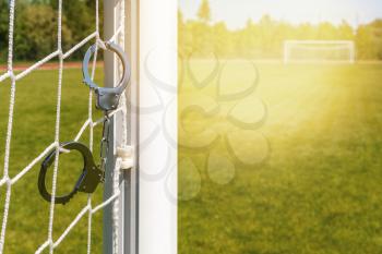 Scam with soccer or football gambling corruption. Handcuffs hanging on the football goals