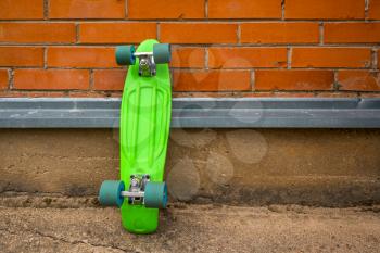 Youth culture.Green skateboard leaning against brick wall.