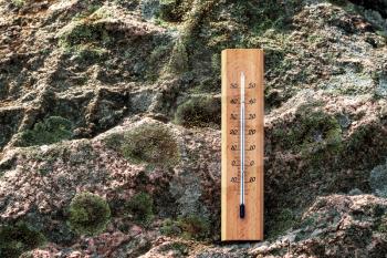 Thermometer on the rock.Thermometer with a high temperature reading on a scale. The concept of hot, dangerous weather, global warming.