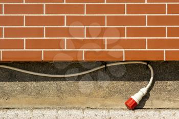 Outdoor electrical extension socket on the brick wall of building with copy space