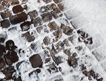 Cobble stone covered by snow and traces