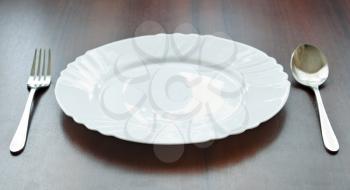 Plate with silverware on wooden table