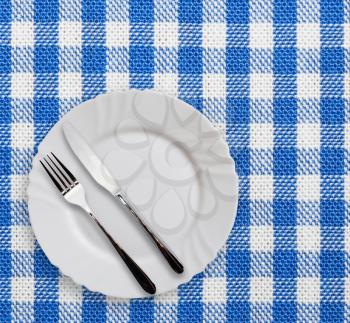 Plate with silverware on checquered blue  background