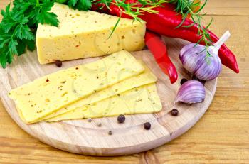 Cheese with spices and herbs, parsley, tarragon, sweet and spicy red pepper, bell pepper, garlic on a round wooden board