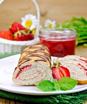 Biscuit roulade with cream and jam, jar of jam, napkin, chamomile, strawberries, mint on the background of wooden boards