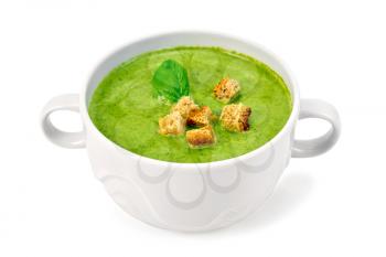 Green soup puree in a white bowl with croutons and spinach leaves isolated on white background