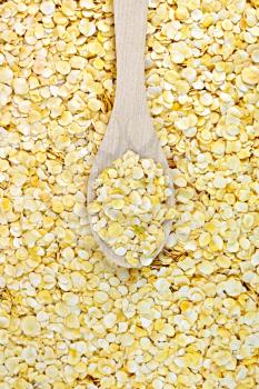 The texture of the yellow pea flakes with a wooden spoon