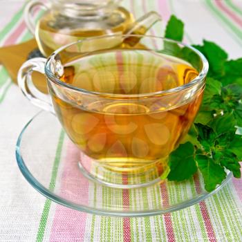 Herbal tea in a glass cup and teapot, fresh mint leaves on a background of a linen tablecloth