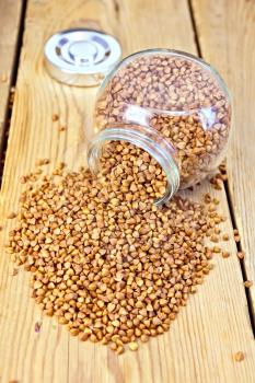 Buckwheat in a glass jar and on the table on a wooden boards background