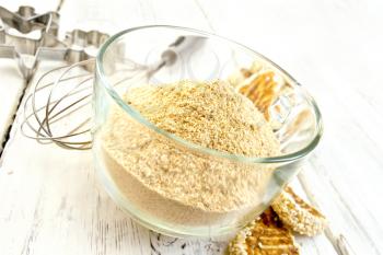 Sesame flour in a glass cupl with a mixer and molds for cookies, sesame seeds, cookies on a wooden boards background