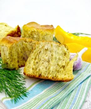 Pumpkin Scones with garlic and dill on a green kitchen towel, yellow pumpkin slices on the background light wooden boards