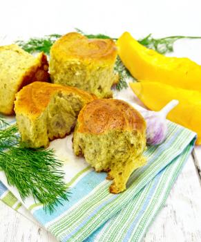 Pumpkin Scones with garlic and dill on a kitchen towel, yellow pumpkin slices on the background light wooden boards
