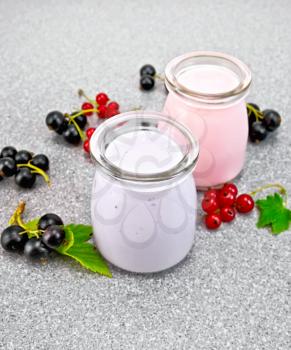 Milk cocktail with black and red currant in glass jars with berries on the background of a granite table