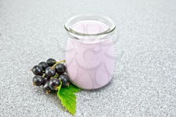 Milk cocktail with black currant in a glass jar with berries on a gray granite table background