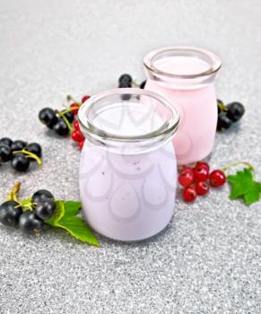 Milk cocktail with black and red currant in glass jars with berries on the background of a stone table