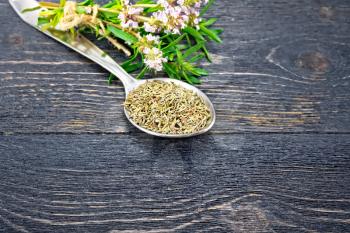 Thyme dry in a metal spoon, a bunch of fresh herbs with flowers on a wooden board background