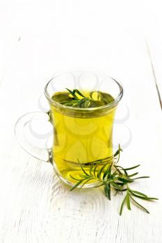 Rosemary herbal tea in a mug on a wooden board background
