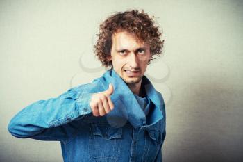 Curly man showing thumbs up. Gesture Okay, cool, good, excellent. On a gray background.
