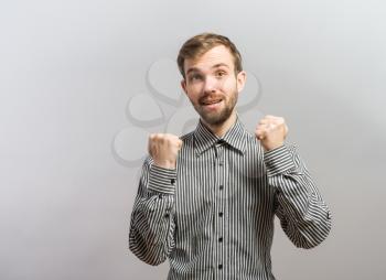 handsome excited man happy smile looking at camera, hold arm hands fist raised up gesture, young guy wear shirt