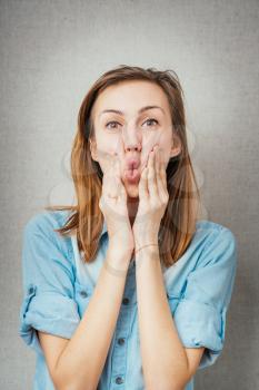 woman grimace hands on cheeks. isolated on gray background