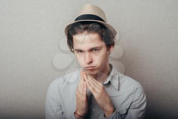 young man  in hat showing clasped hands on top isolated grey wall background