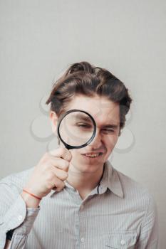 young man looking through a magnifying glass