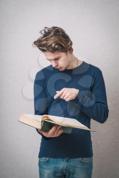 Young woman reading a book and points that I found what I was looking. On a gray background.