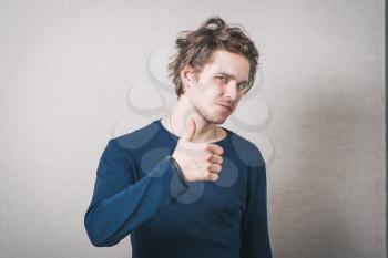 Man showing thumb up. Gray background.