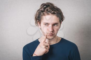 Man thinking with finger on the cheek, a toothache. Gray background.