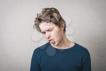 Man sticking his tongue out, pretended to be dead. Gray background