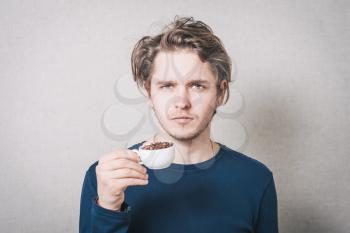 Man with a cup of coffee beans. Gray background
