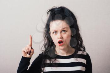 A woman shows a finger up the idea. Gray background.