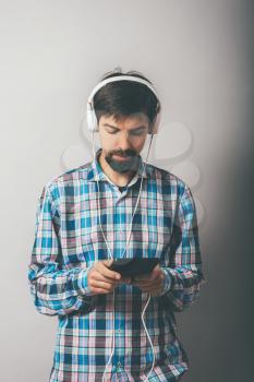 bearded hipster listening to music on headphones with the phone