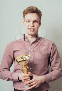 young man won and holds the cup in his hands