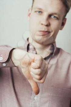 disappointed young man showing thumb down sign