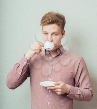 man drinks coffee from a small white cup of coffee