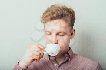 man drinks coffee from a small white cup of coffee