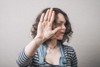 A woman shows a gesture stop. On a gray background.