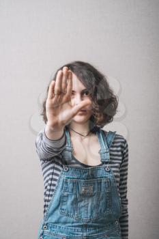 A woman shows a gesture stop. On a gray background.