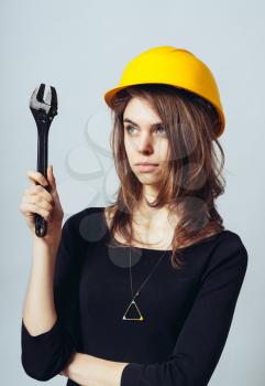 beautiful woman engineer with big screw key in helmet