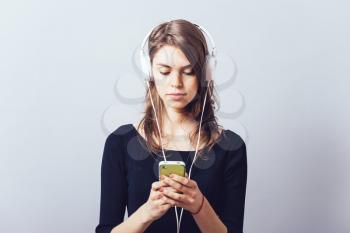 Woman with headphones and listening to music on a grey background