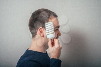 A man with a light bulb economical. On a gray background.