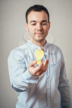 man close-up on a gray background holding a light bulb sticker