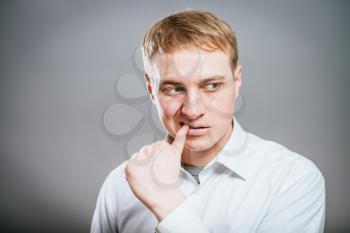 Closeup portrait of man biting his thumb fingernail or finger in mouth, very stressed and nervous, isolated on gray background with copy space