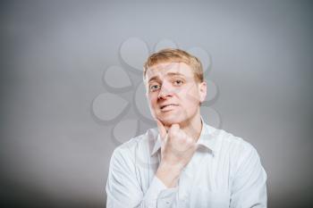young man thinks thinks. head resting on his hand, looking into the camera. Gesture.