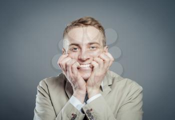 Close up portrait of young smiling businessman covering mouth with his hand while looking at you 
