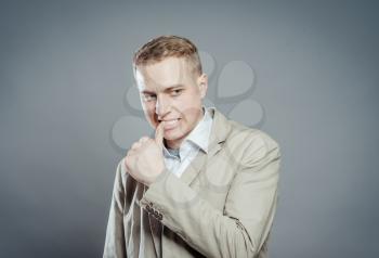 Closeup portrait, young man, thinking, finger on mouth, looking at you, deciding. Human emotions, facial expressions, feelings