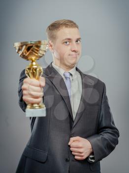 portrait of gesturing fists up businessman with gold cup. Concept of win and success