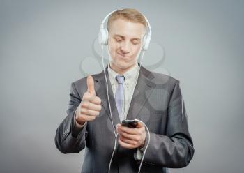 Studio shot of modern  businessman with headphones, listening to music and dancing