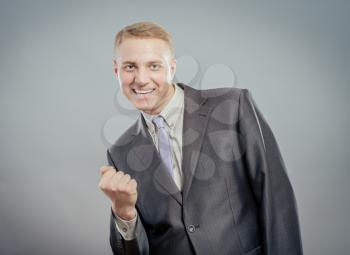 Closeup portrait happy successful business man winning, fists pumped celebrating success isolated grey wall background. Positive human emotion, facial expression. Life perception, achievement